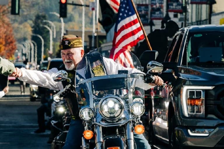 Veterans on motorcycles greeting spectators along Main Street during the Auburn Veterans Parade